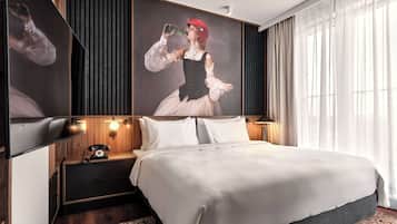 Una habitación de hotel moderna con una cama grande, una mesita de noche con lámpara, un teléfono y un televisor montado en la pared.
