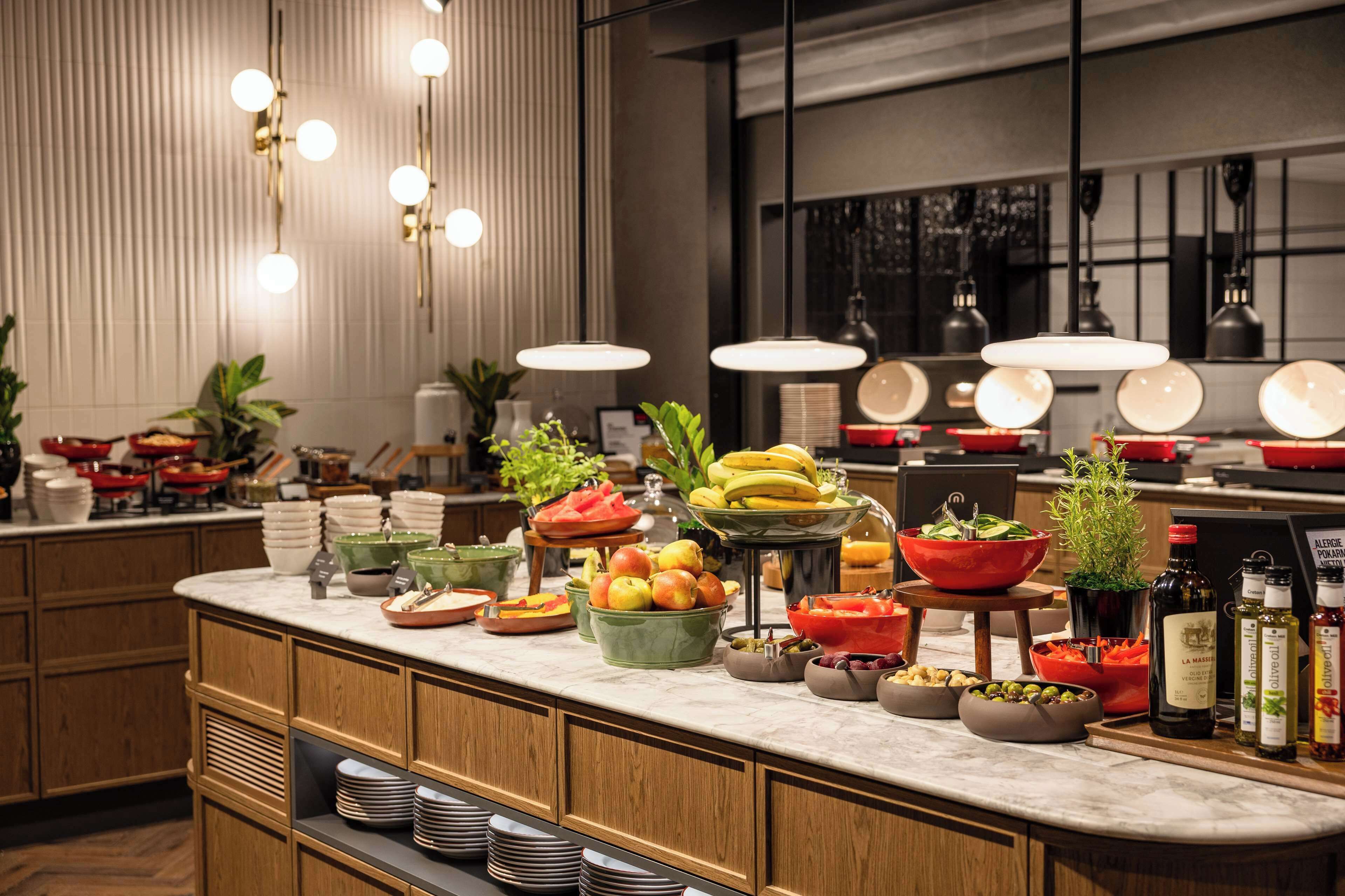 A well-lit kitchen area with a marble countertop, various fruits, vegetables, and condiments.