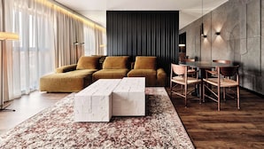 A modern living room with a sectional sofa, a coffee table, and a dining area with chairs and a table. - Radisson RED Hotel & Radisson RED Apartments, Kraków (Kraków)