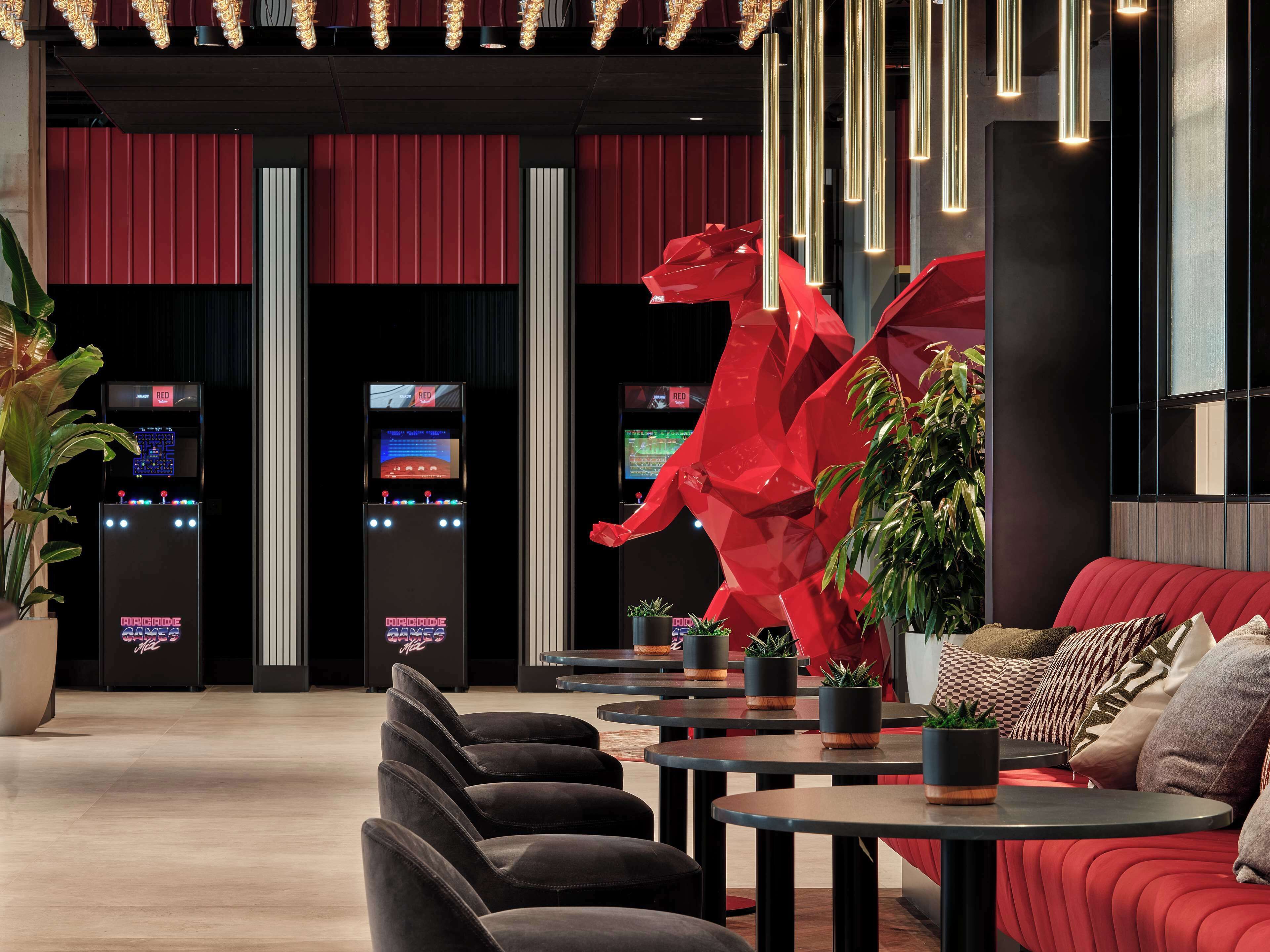 Un interior moderno con asientos rojos, máquinas de juego e iluminación colgante.