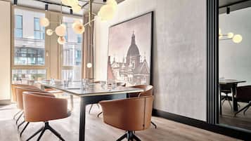 A modern conference room with a large table, leather chairs, and a cityscape painting on the wall.