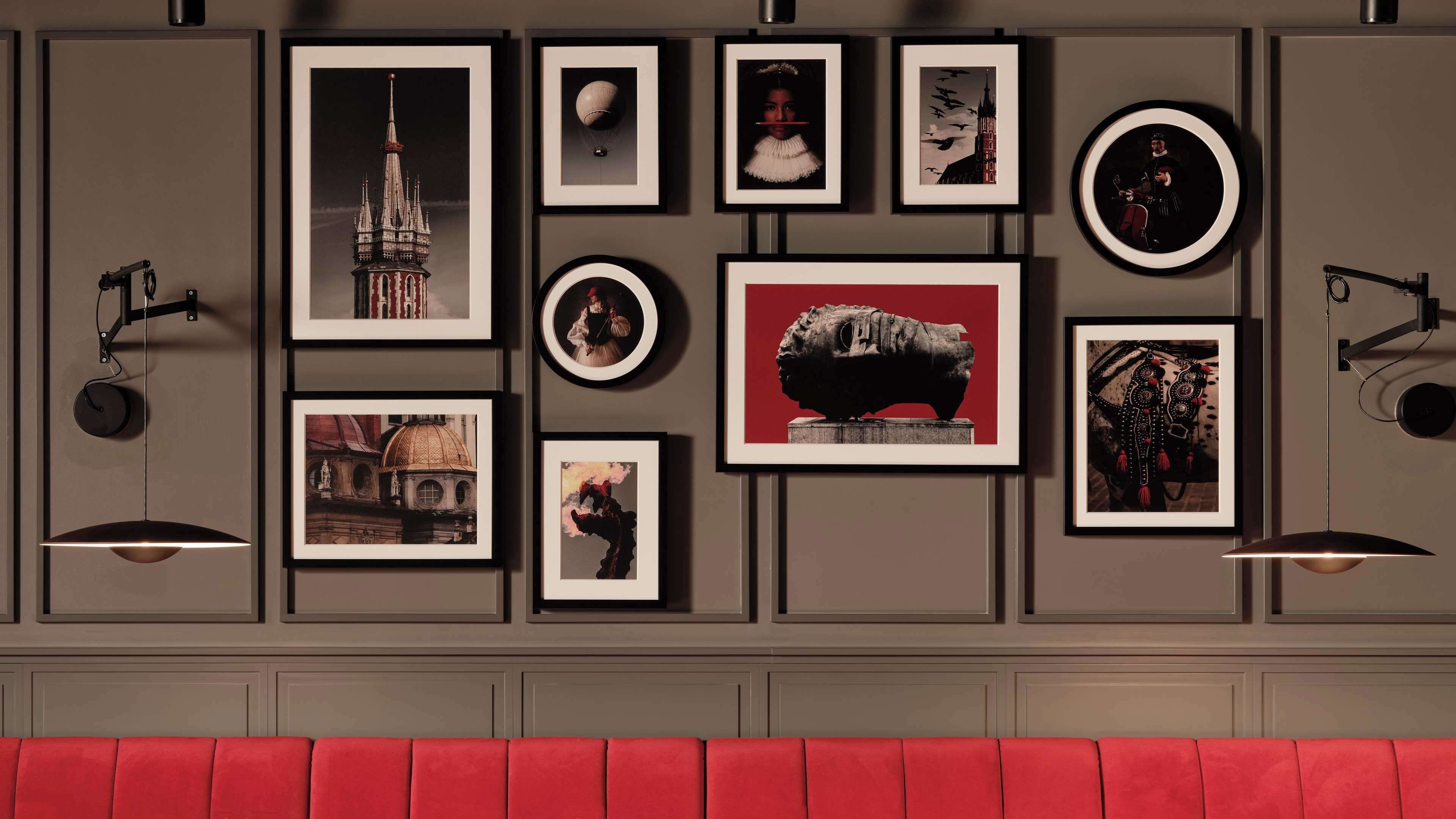 A wall with framed artwork, including a building, a sculpture, and various portraits.