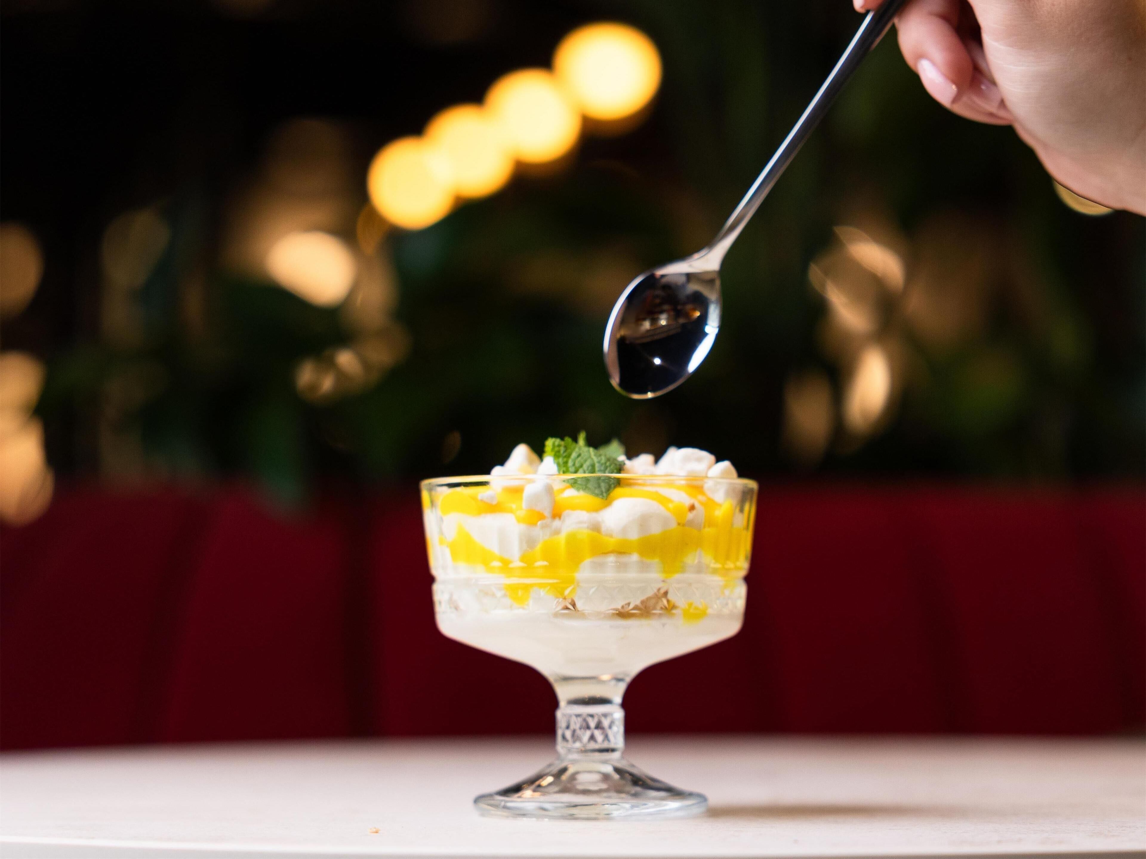 Un postre en un bol de vidrio con una cuchara encima.