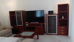 Ein Wohnzimmer mit einer Couch, einem Couchtisch, einem Fernseher und Holzkredänzen.