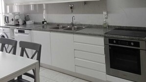 Eine moderne Küche mit weißen Schränken, einer Edelstahl-Spüle, einem eingebauten Backofen und einer Kaffeemaschine.