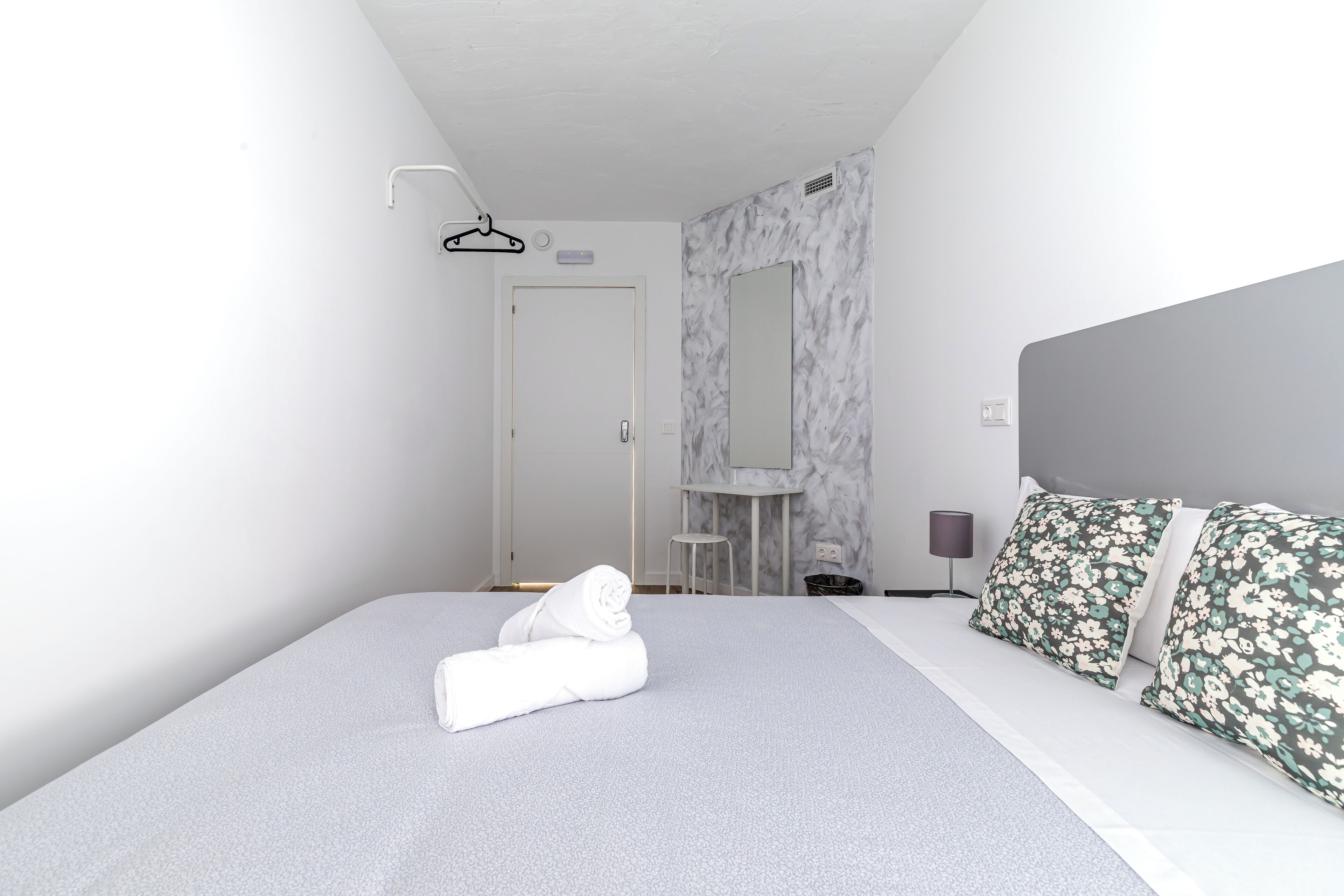 Ein modernes Hotelzimmer mit einem ordentlich bezogenen Bett, einem Badezimmer mit Marmorwand und einem Nachttisch mit Lampe.