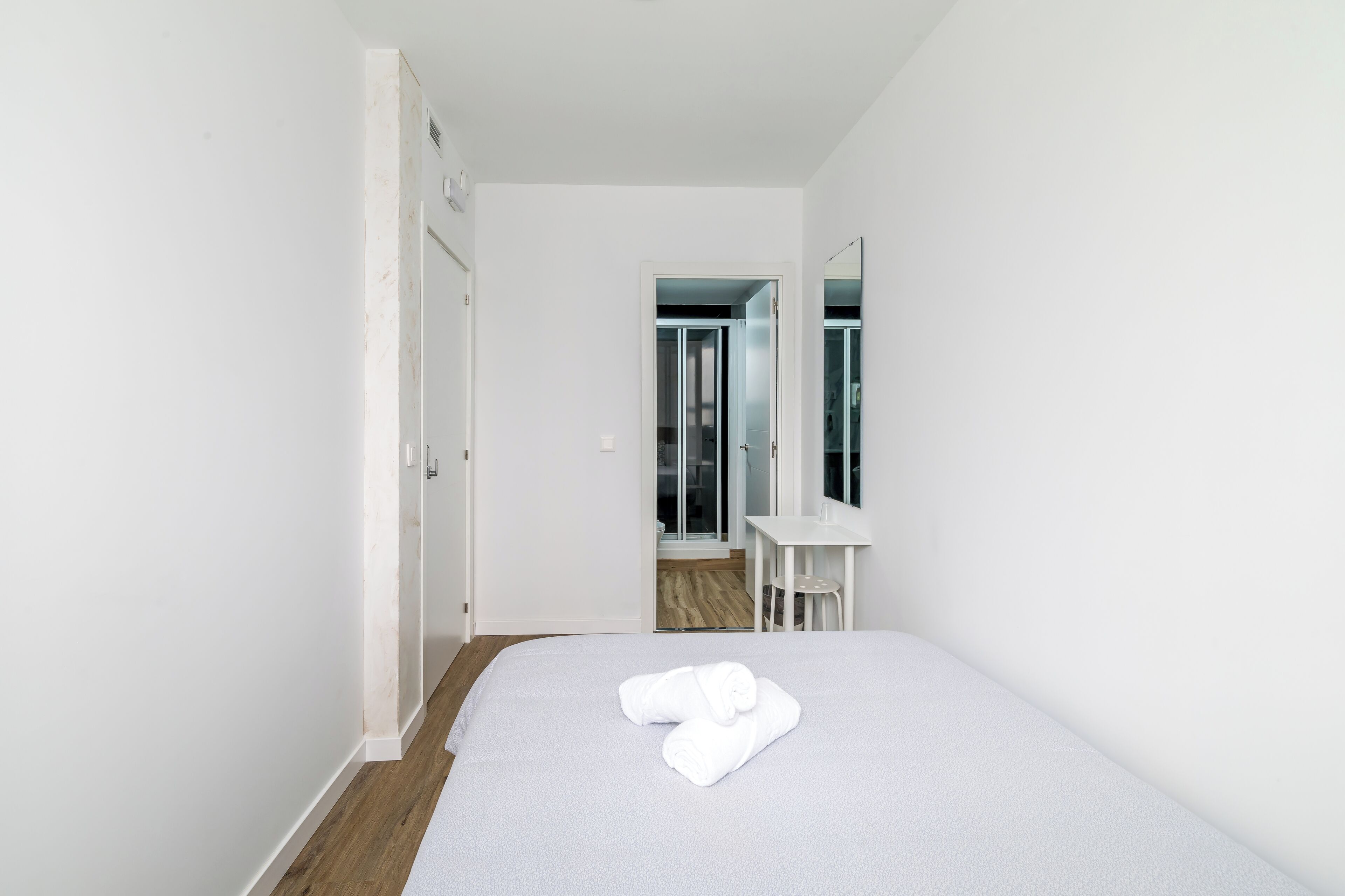 A hotel room with a bed, a desk, and a mirror.