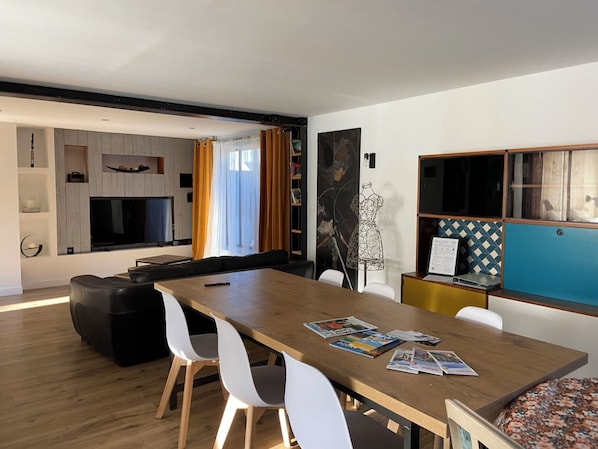 Ein modernes Wohnzimmer mit Essbereich, Küche und einer Sitzecke mit Fernseher.