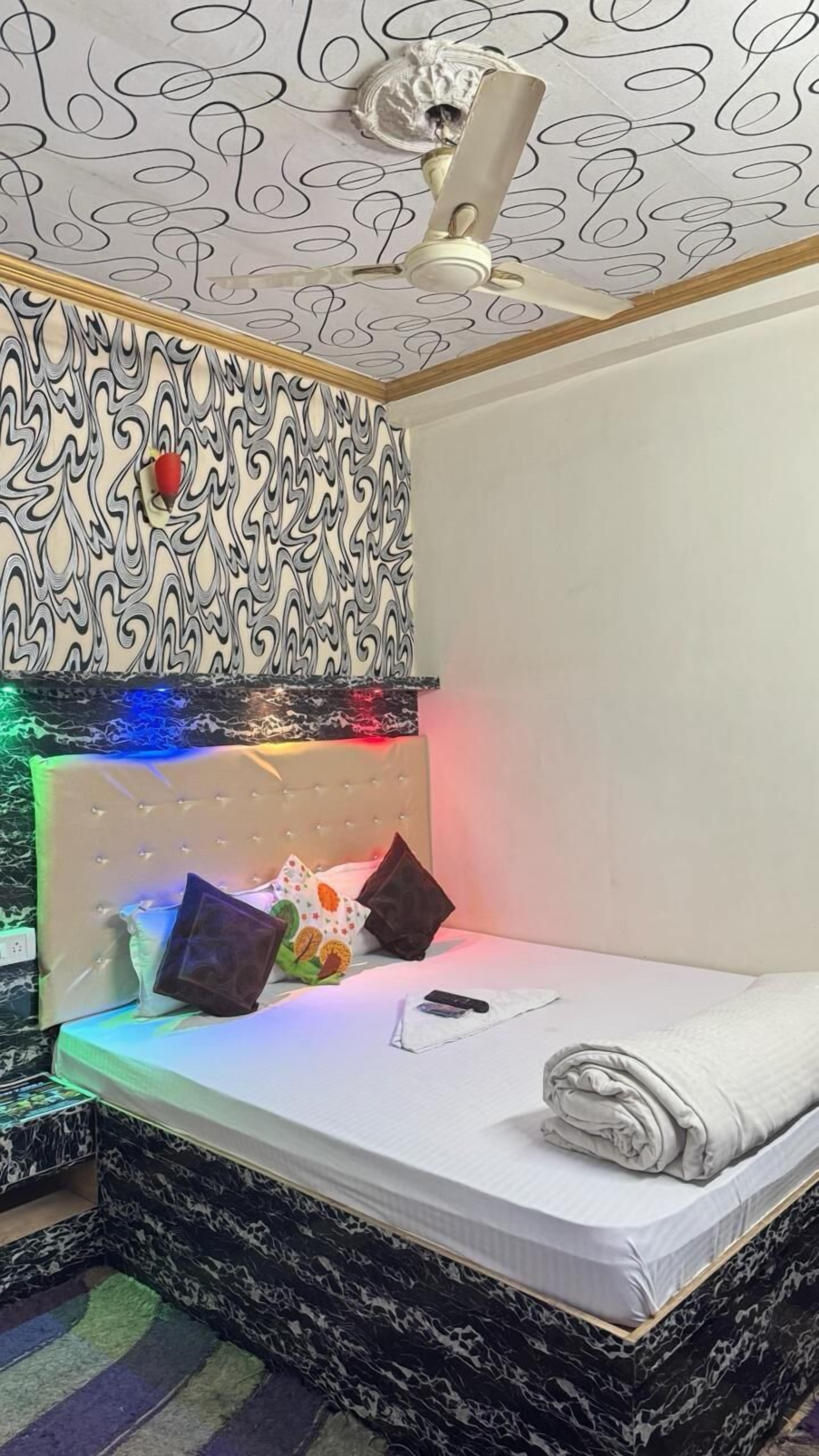 A bedroom with a bed, a ceiling fan, and a patterned wall.
