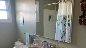 Un baño con lavamanos de granito, inodoro, espejo y toallero.