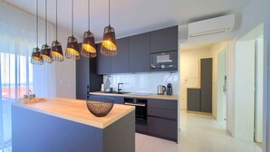 Una cocina moderna con una isla central, iluminación colgante y vistas al exterior.