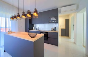 A modern kitchen with a central island, pendant lighting, and a view to the outside.