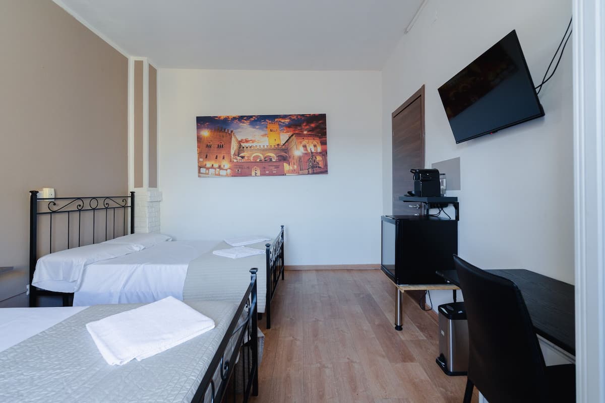 Ein Hotelzimmer mit zwei Betten, einem Schreibtisch, einem Fernseher und einem Gemälde eines Schlosses.