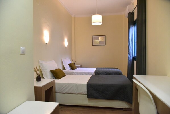 A hotel room with two beds, a bedside table with a vase, a hanging light, and a window with curtains. - Modern apartment, in the heart of the Old Harbour of Chania, 50m from the sea! (Chania)
