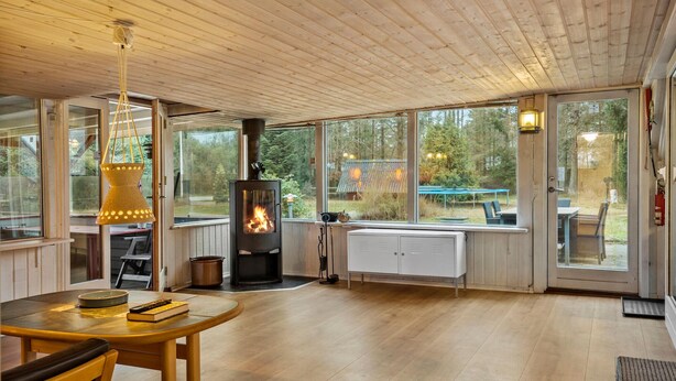 A cozy cabin interior with a wood-burning stove, large windows, and a dining area. - 4 bedroom cozy home in Ans By (Ans By)