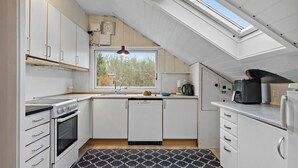 A modern kitchen with white cabinets, a built-in oven, a dishwasher, and a coffee maker. - 4 bedroom cozy home in Ans By (Ans By)