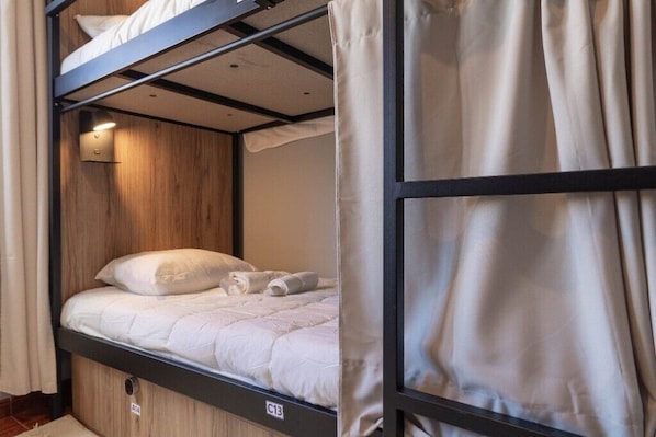 Een stapelbed met een houten hoofdbord, een wit matras en een opgerolde handdoek.