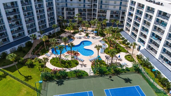 A multi-story hotel with a central swimming pool surrounded by palm trees and sun loungers. - Snowbird Rates Gulf Views Beach Pool Sleeps 4 (Gulf Shores)