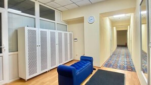 Un couloir avec un canapé bleu, une horloge et un tapis à motifs.
