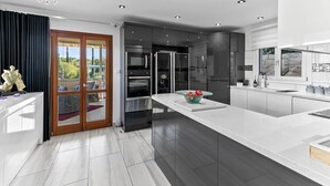 A modern kitchen with a large island, built-in appliances, and a view to the outdoors. - Junior Villa JZ02 - Eleyjo (Kouklia)