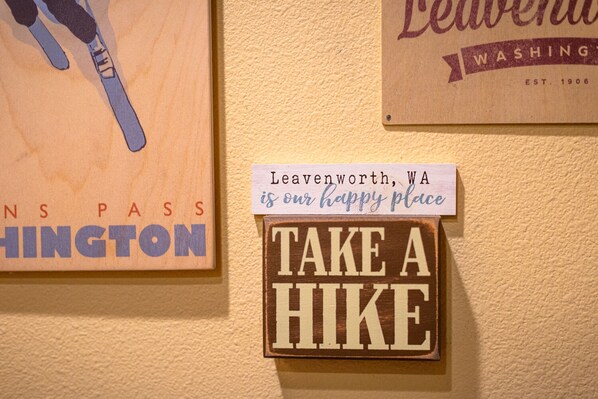 A wall with signs including "Leavenworth, WA is our happy place" and "TAKE A HIKE". - Harlin Haus at Cascade Crest Condos (Leavenworth)