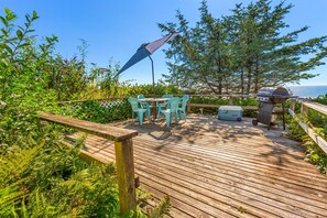 A wooden deck with outdoor furniture, a grill, and a view of the sea. - The Searise Cottage in Hoquiam (Moclips)