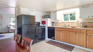 A kitchen with white cabinets, a refrigerator, an oven, a microwave, and wooden cabinets. - Crabbin Cabin Westport (Westport)