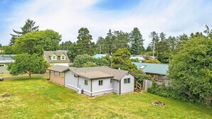 A single-story house with a fenced yard, surrounded by trees and other houses. - Crabbin Cabin Westport (Westport)
