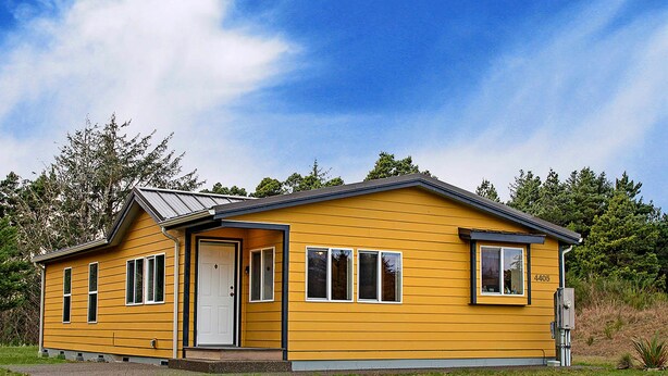 A yellow single-story house with a front door, two windows on the side, and a garage door. - Spyglass Dunes in Grayland (Grayland)