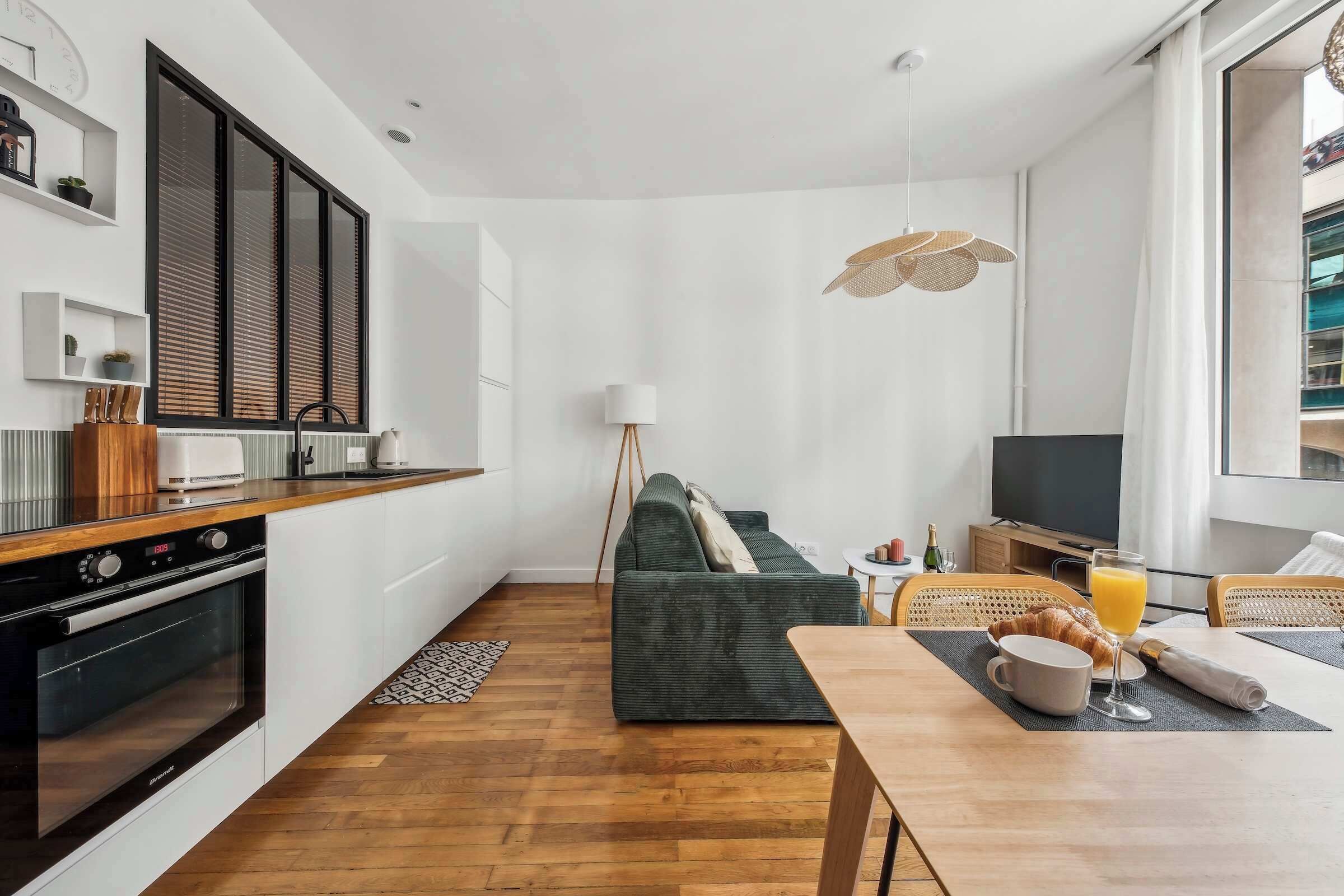 A modern kitchen with a built-in oven, a dining area with a table set for breakfast, and a cozy seating area with a sofa.