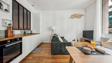 A modern kitchen with a built-in oven, a dining area with a table set for breakfast, and a cozy seating area with a sofa.