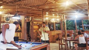 An outdoor wooden deck with a pool table, seating areas, and a bar. - Raffiel Nias  (Nias)