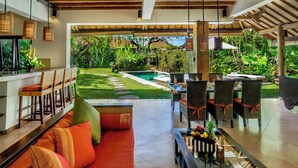 A modern outdoor living area with a pool, dining setup, and a cozy seating area. - Hevea Villas (Seminyak)