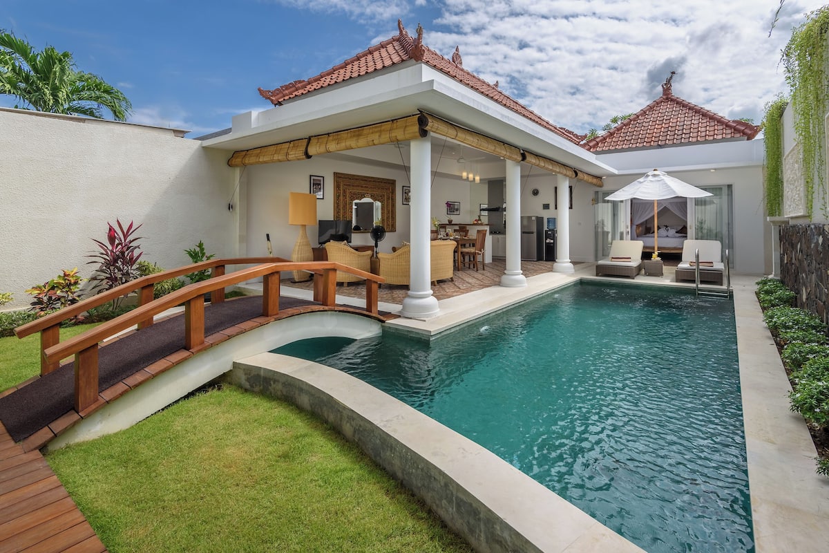 Una casa moderna con piscina, un porche cubierto y un puente de madera.
