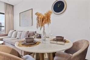 Ein moderner Essbereich mit einem runden Tisch, Stühlen und einer Vase mit Trockenpflanzen.