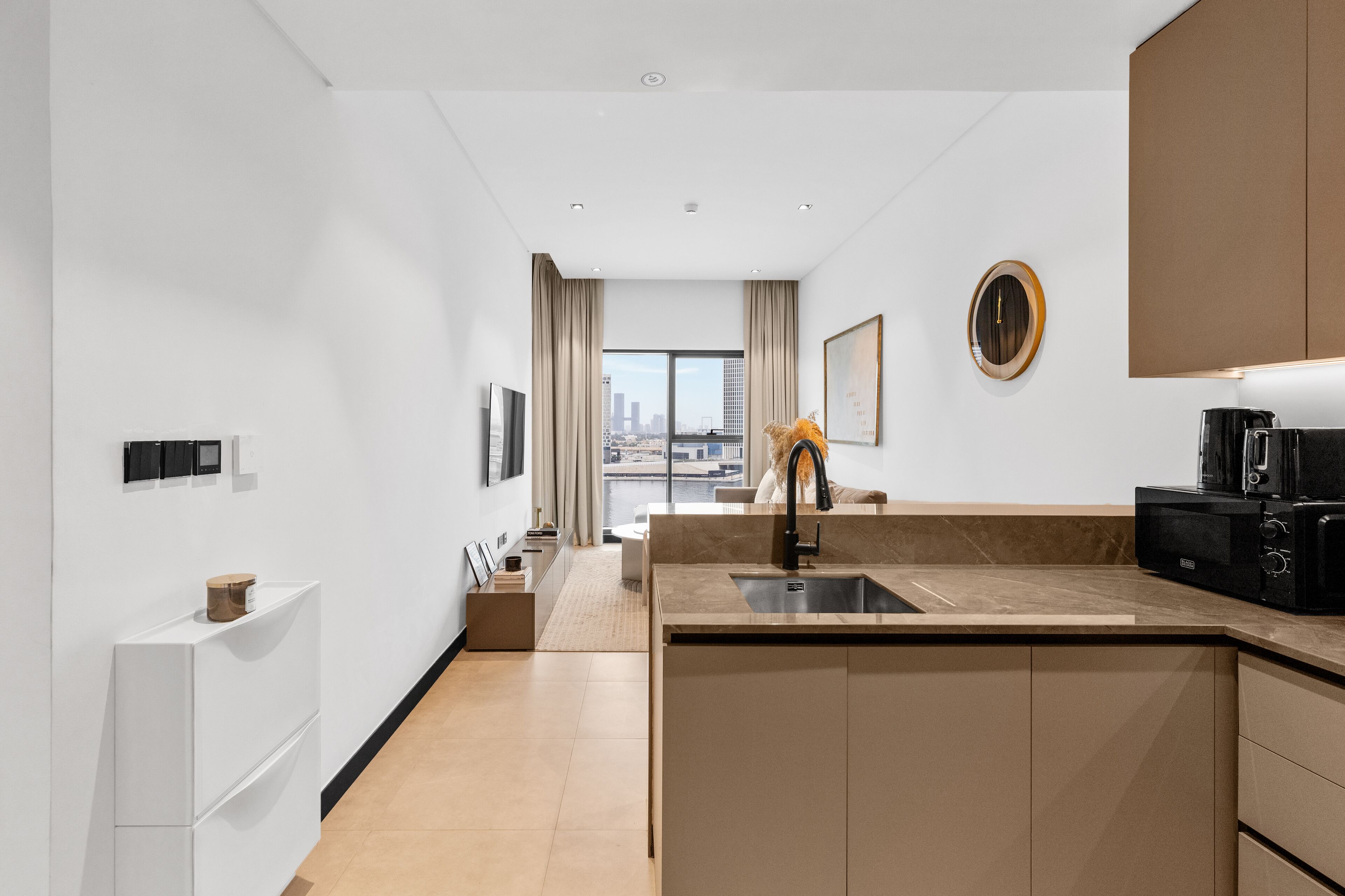 A modern kitchen with a large island, a built-in oven, and a view of the city through large windows.