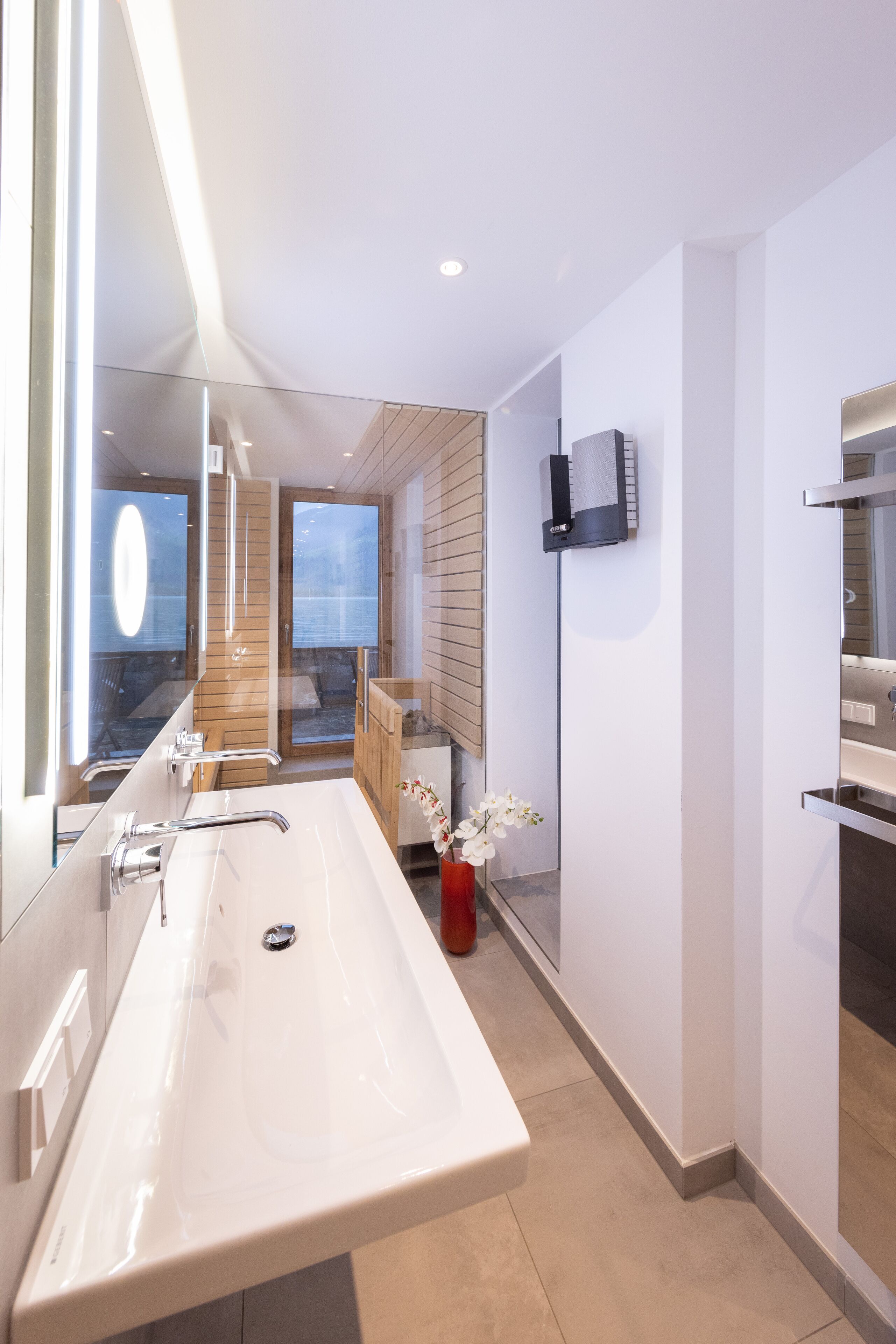 Un baño moderno con un lavamanos grande de color blanco, un espejo y un mueble de madera.