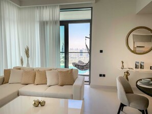 Relax in a stylish living room with a large sofa, a hanging chair, and a city view.