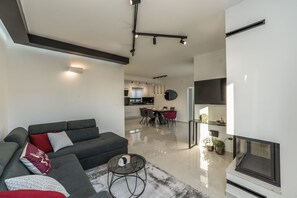 Un saló modern amb un sofà gris, una taula de centre de vidre i una llar de foc.
