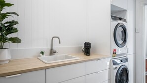 Een moderne keuken met een spoelbak, koffiezetapparaat en een voorlader wasmachine.