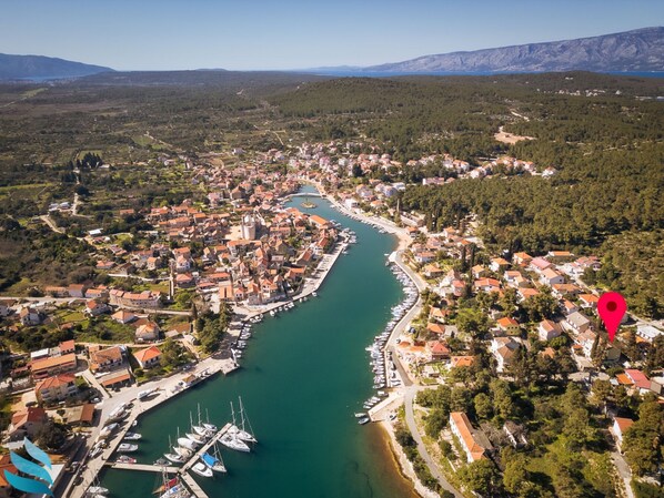 An aerial view of a coastal town with a marina, dense housing, and surrounding hills. - Hvar spa & Apartments (Jelsa)