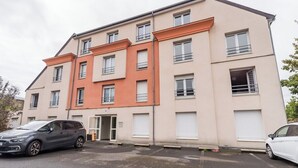 Un edificio de apartamentos de varios pisos con un área de estacionamiento al frente.