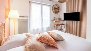Un dormitorio con una cama, televisión montada en la pared, un escritorio y una silla.