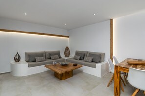 Relax in this serene living space, featuring a central coffee table, plush sofa, and dining area.