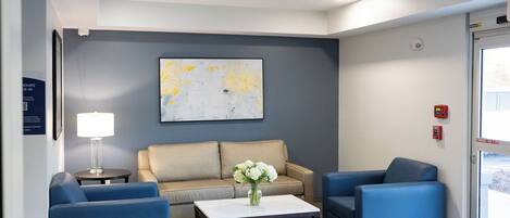 A modern waiting area with a sofa, two armchairs, a coffee table, and a vase of flowers.