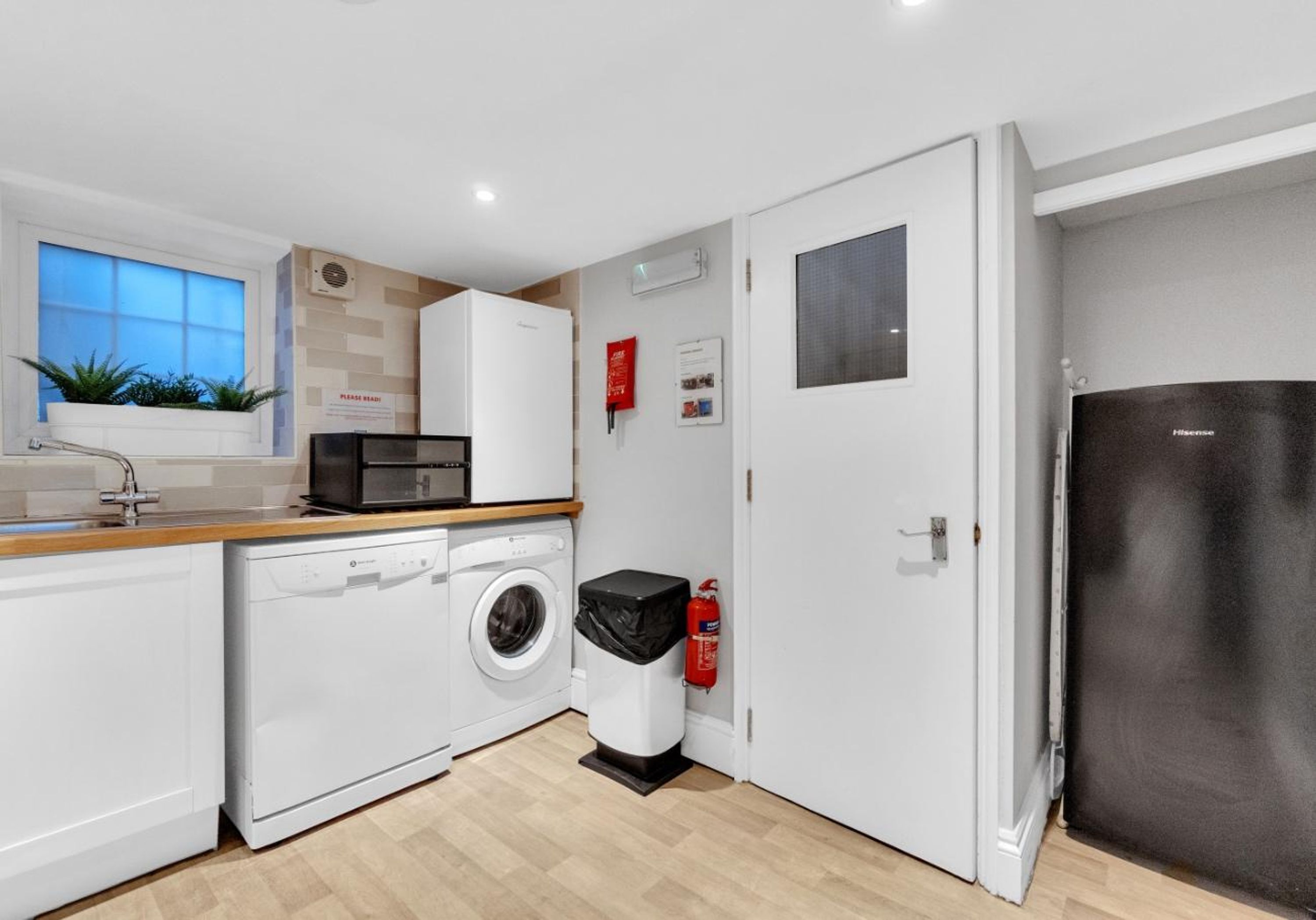 A compact kitchen with a washing machine, a microwave, and a refrigerator.