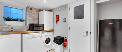 A compact kitchen with a washing machine, a microwave, and a refrigerator.