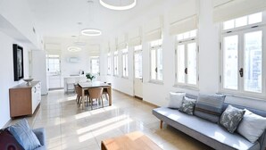 En rummelig opholdsstue med sofa, spisebord og køkken i baggrunden.