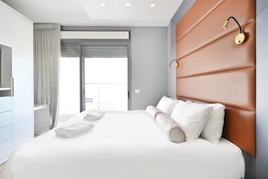 Una habitación de hotel moderna con una cama grande, televisión, balcón y lámpara fijada a la pared.