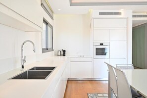 Eine moderne Küche mit weißen Schränken, einer Edelstahl-Spüle und einem eingebauten Backofen.